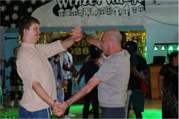 A young person and a member of staff dancing together on the prom dance floor