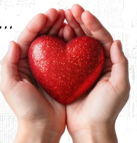 A pair of cupped hands holding a sparkling red heart